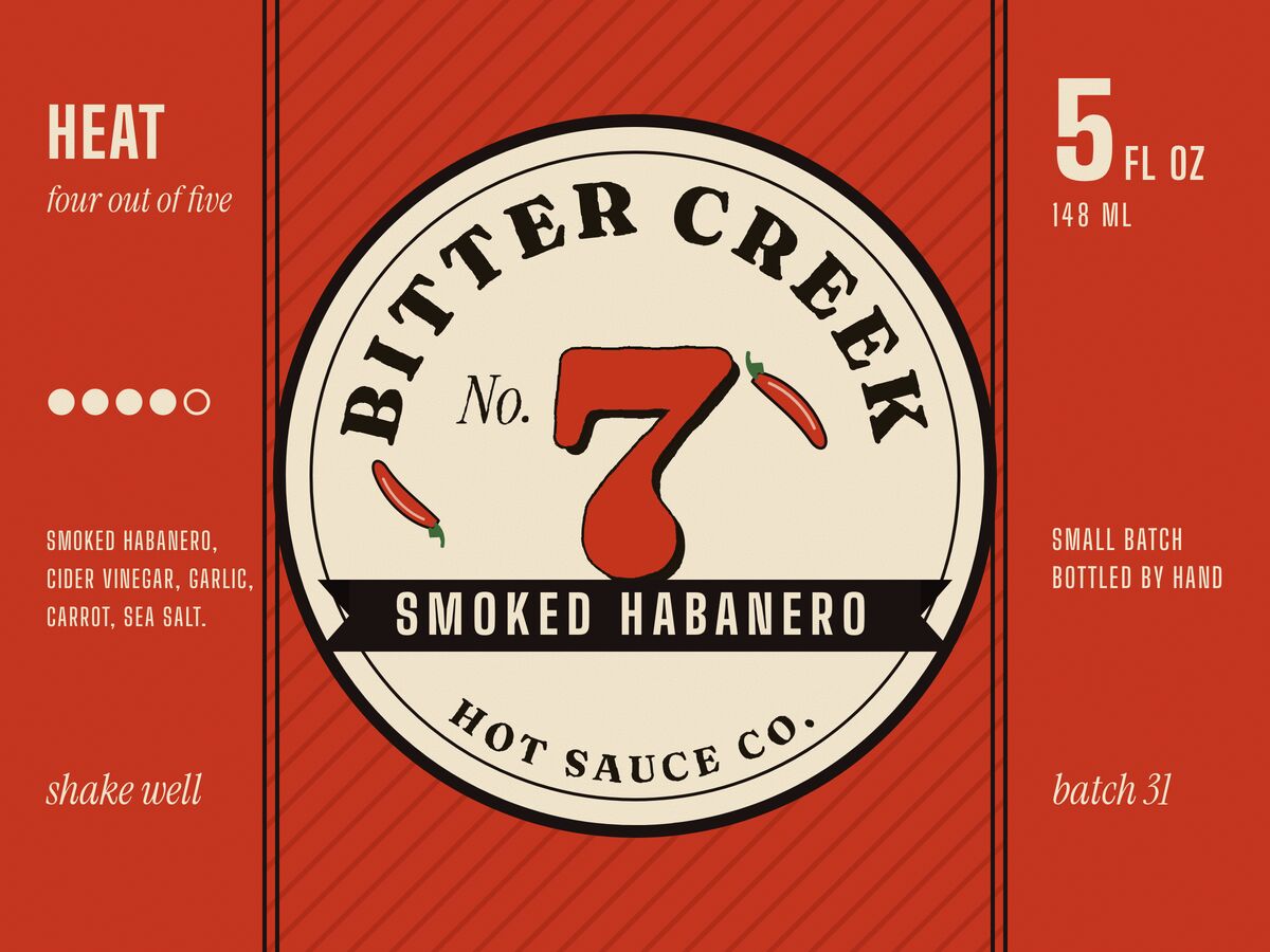 A hot-sauce label on tomato red: a cream roundel lettered BITTER CREEK around a big red No. 7, two drawn chillies and a black SMOKED HABANERO ribbon