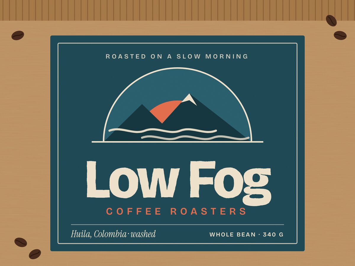 A kraft coffee bag with a teal label: a coral sun behind a dark peak and drifting fog, the words Low Fog lettered in cream
